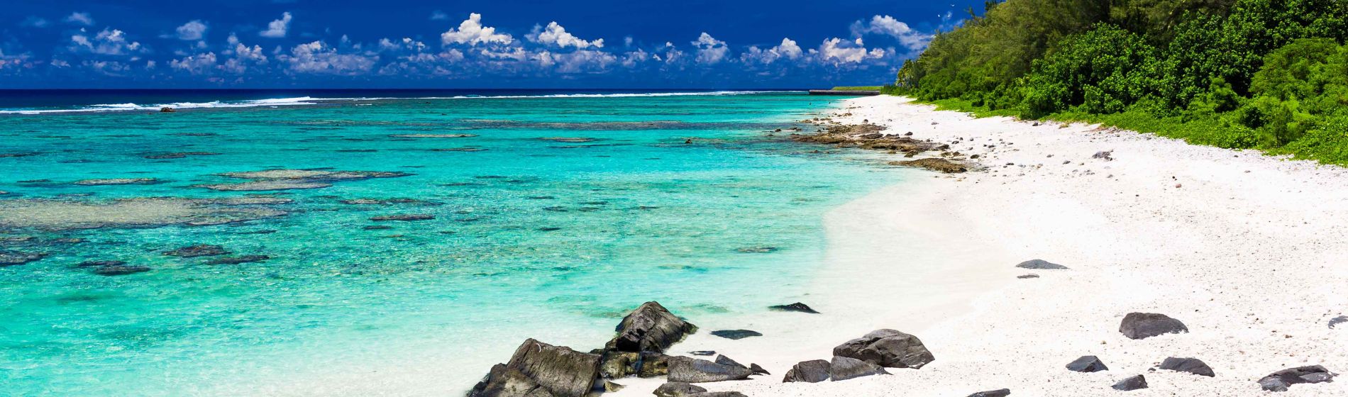 schoener_strand_mit_weissem_sand_und_schwarzen_felsen_auf_rarotonga.jpg